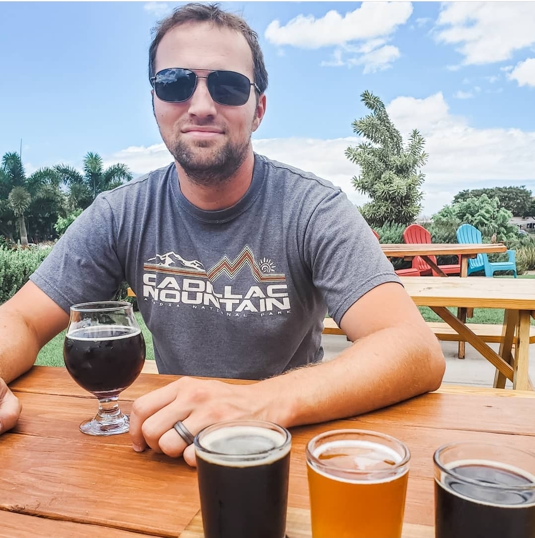 Keith at outdoor brewery with goblet of beer in front of him